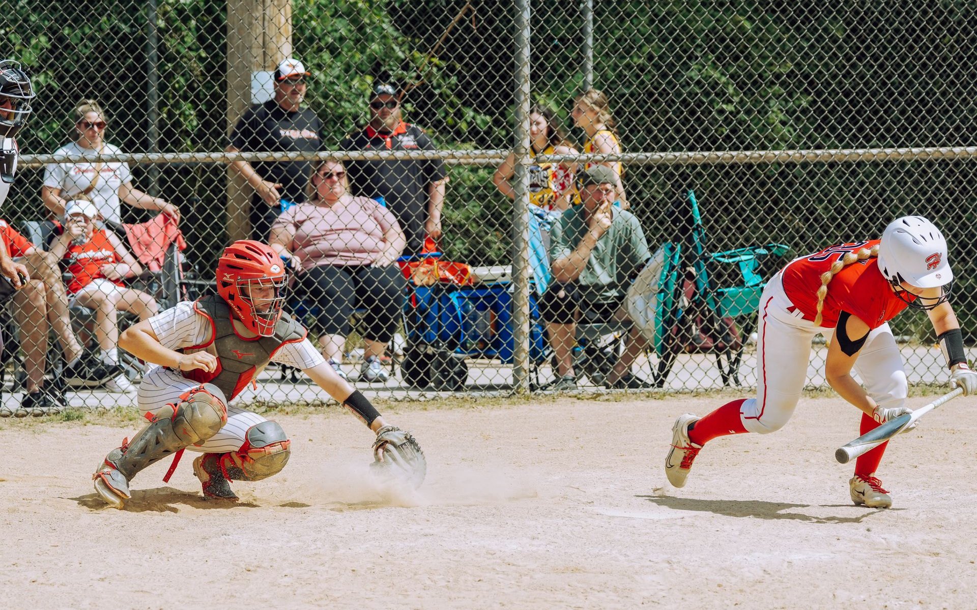 Youth baseball players competing during a community game with spectators nearby